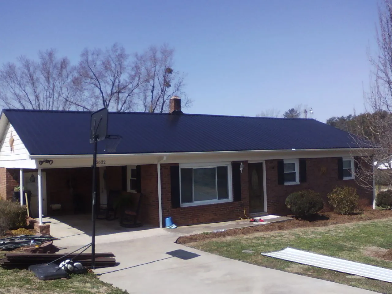 Finished dark blue metal roof on a brick ranch with a carport in Norfolk
