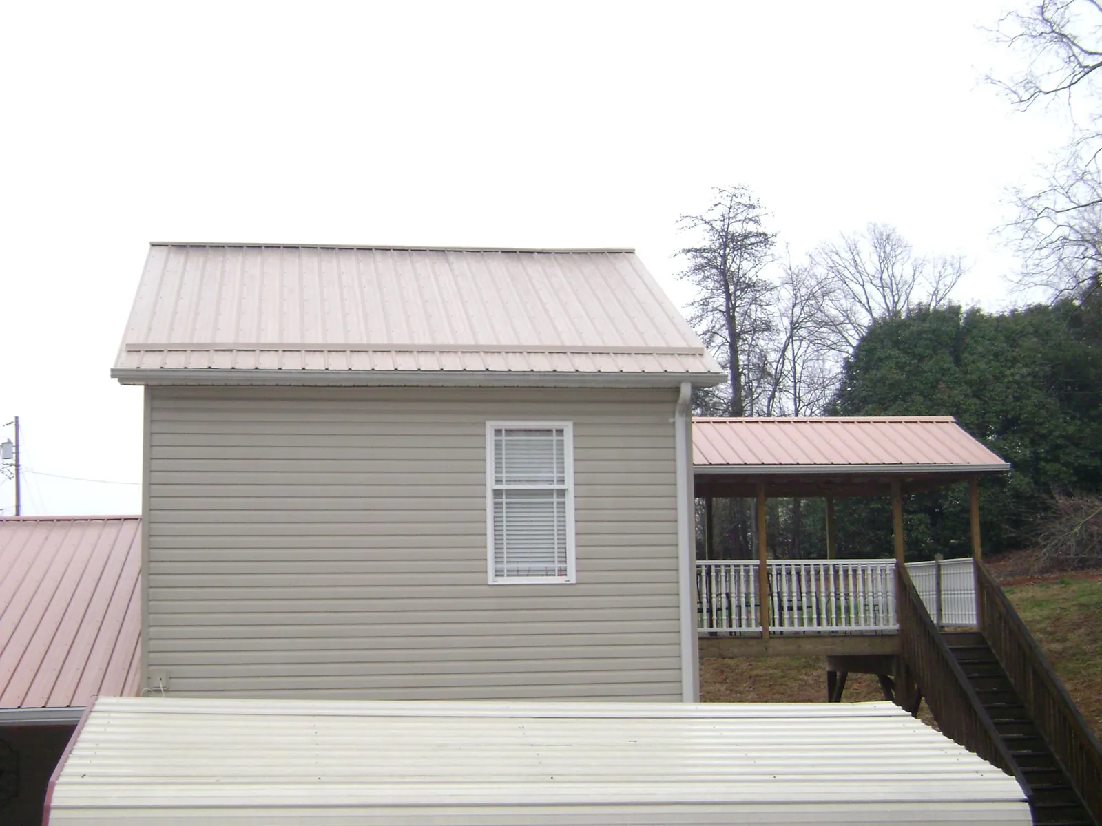 Tan metal roofs on a two story addition and attached porch, from a Roof Replacement job in Norfolk